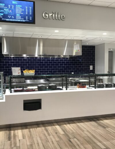 Modern cafeteria with blue tile backsplash and serving counters without food.