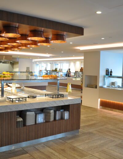 Modern and well-lit hotel buffet area with food stations and seating space in the background.