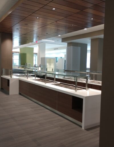 Modern office cafeteria with empty serving counters and a wooden ceiling.