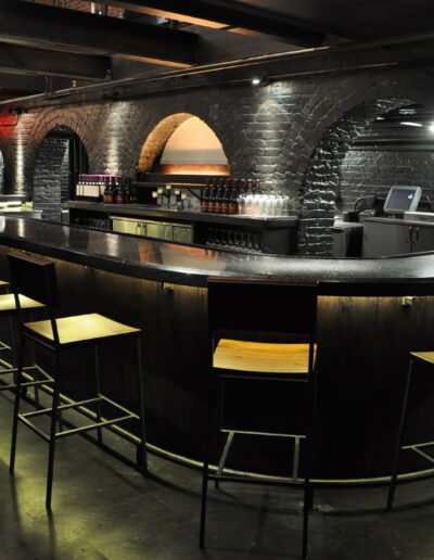 Empty bar interior with black stools and arched walls.
