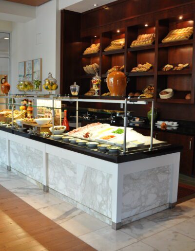A well-organized hotel buffet with a variety of food displayed on counters and shelves.