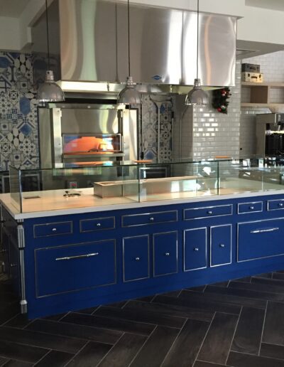Modern kitchen with blue cabinets, stainless steel appliances, and a pizza oven.