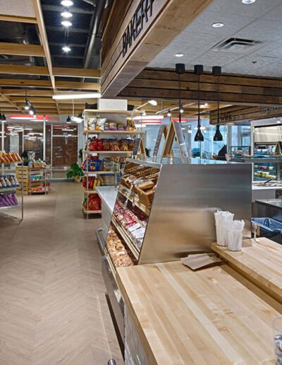 Modern grocery store interior with a variety of packaged goods on shelves and a deli counter on the right.